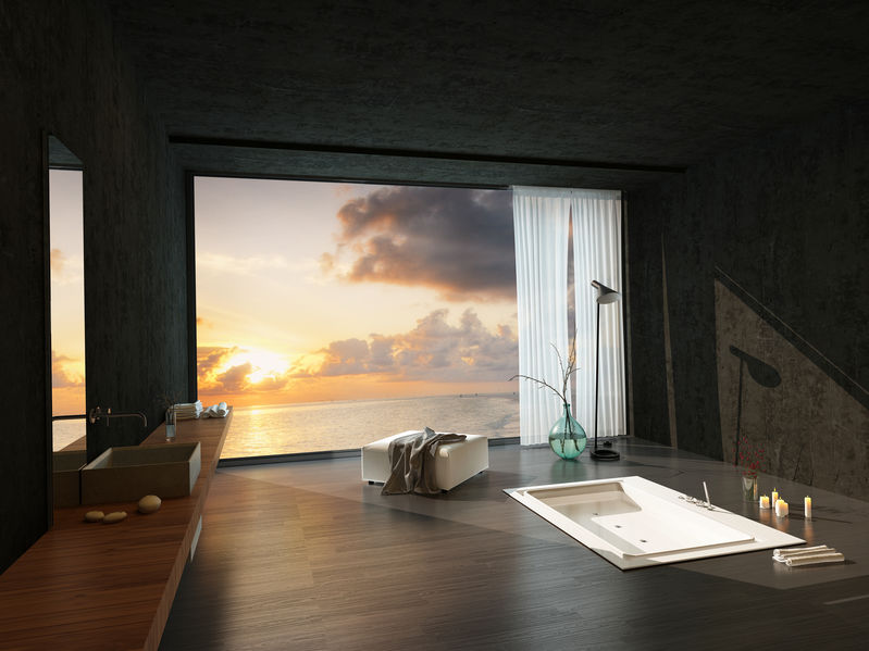 Sunken bathtub in a modern luxury bathroom with a colorful sunset visible through the large window